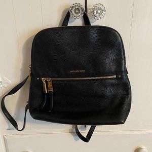 Black Michael Kors backpack with gold zipper detail.